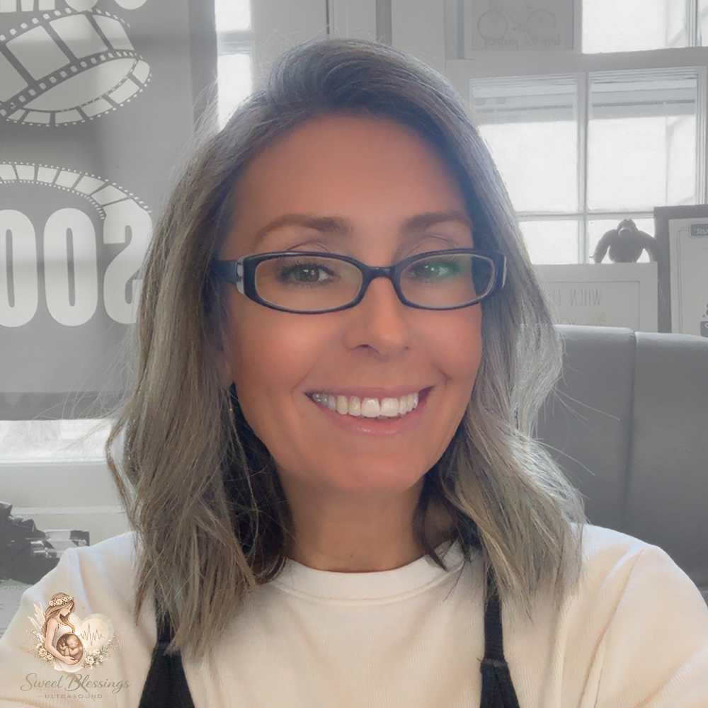 Smiling woman with glasses in a bright office, wearing a white shirt and black lanyard.