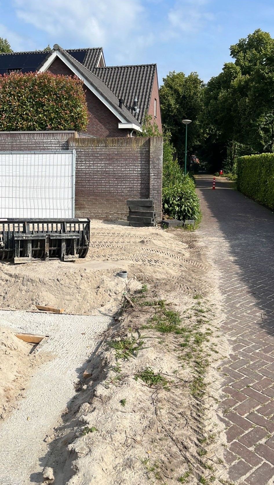 een bakstenen oprit met een wit hek en een bakstenen huis op de achtergrond