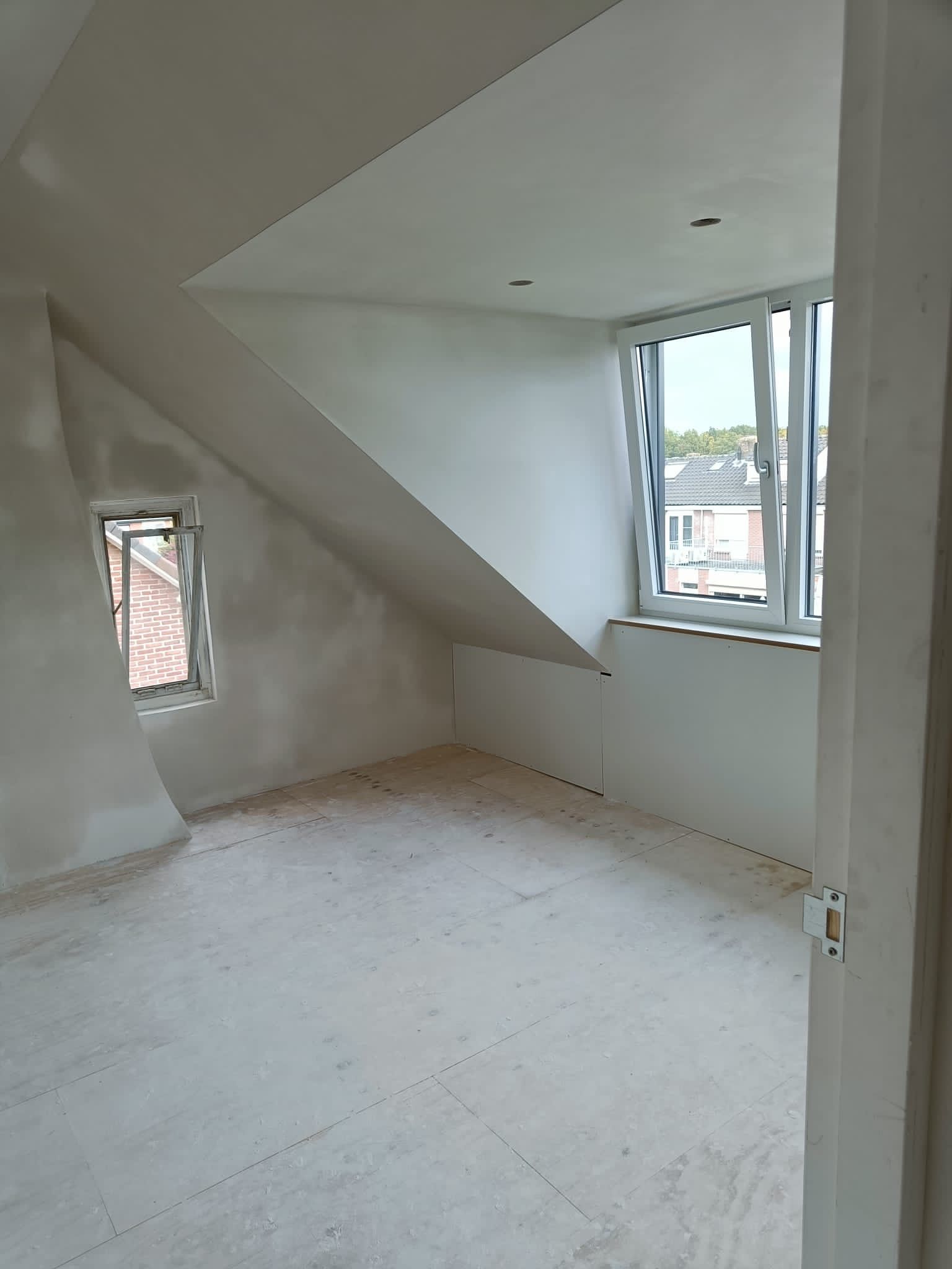 een lege kamer met een raam en een bakstenen muur