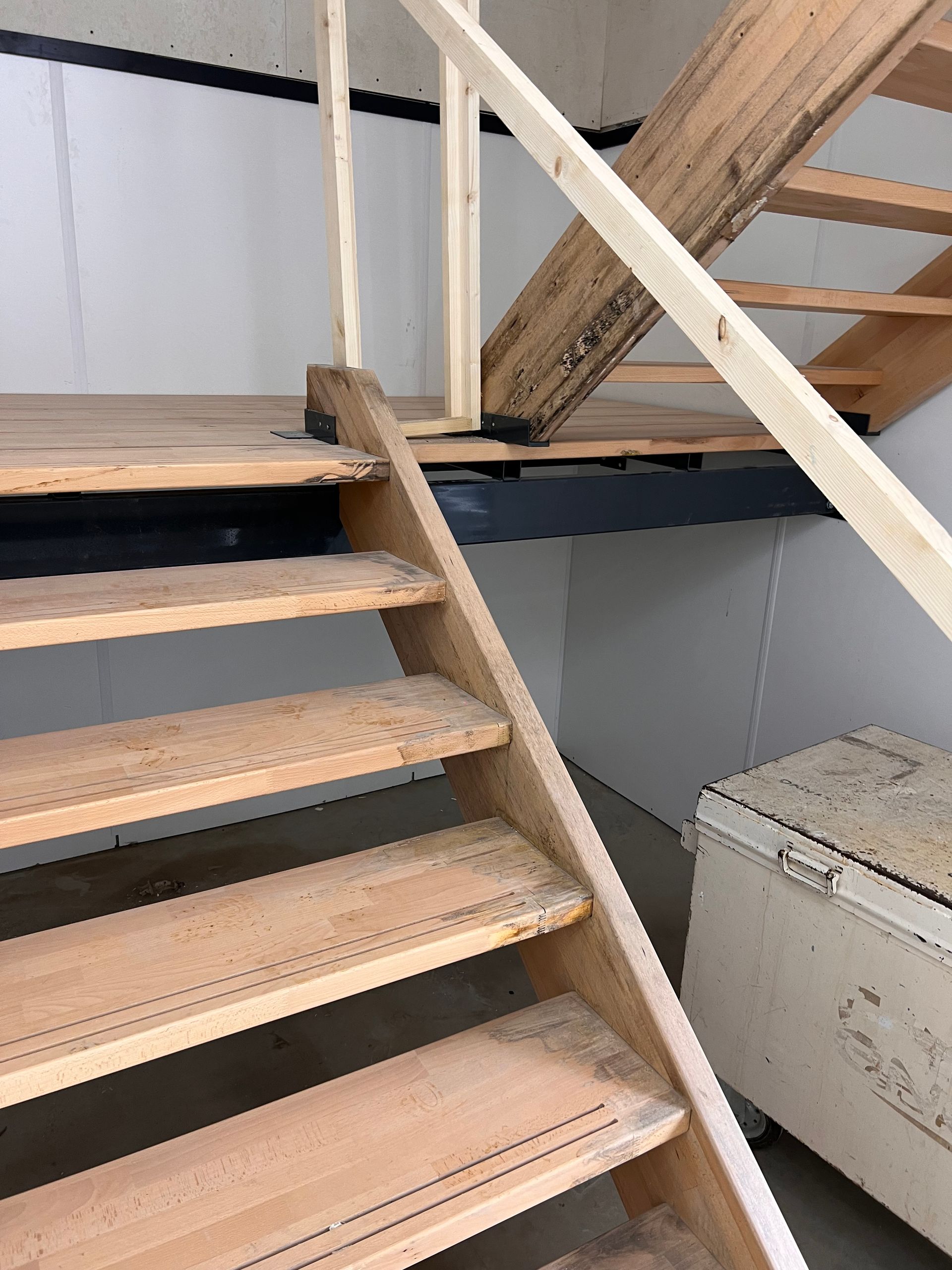 er wordt een houten trap met een metalen leuning gebouwd