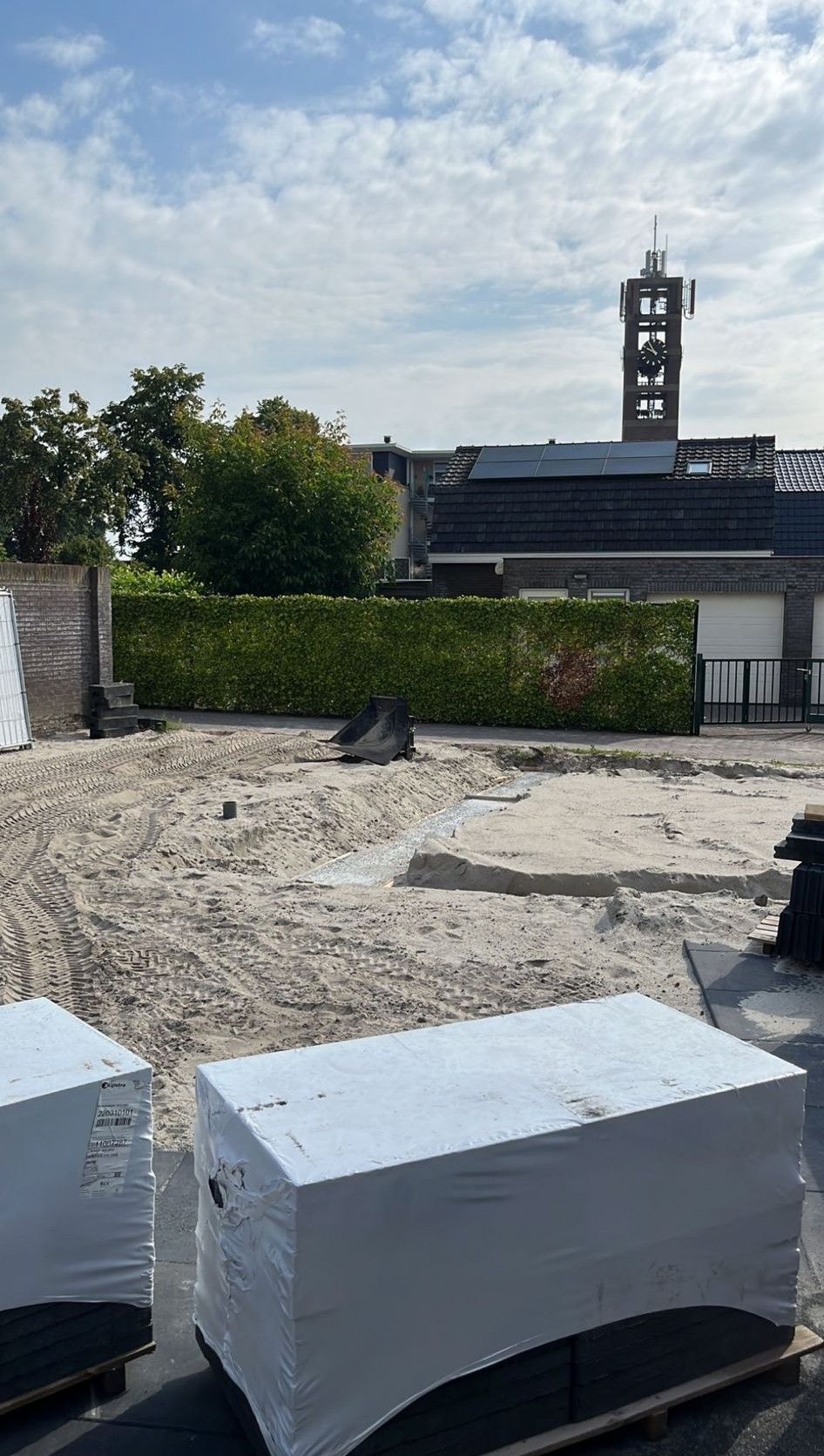 een gebouw in aanbouw met een toren op de achtergrond