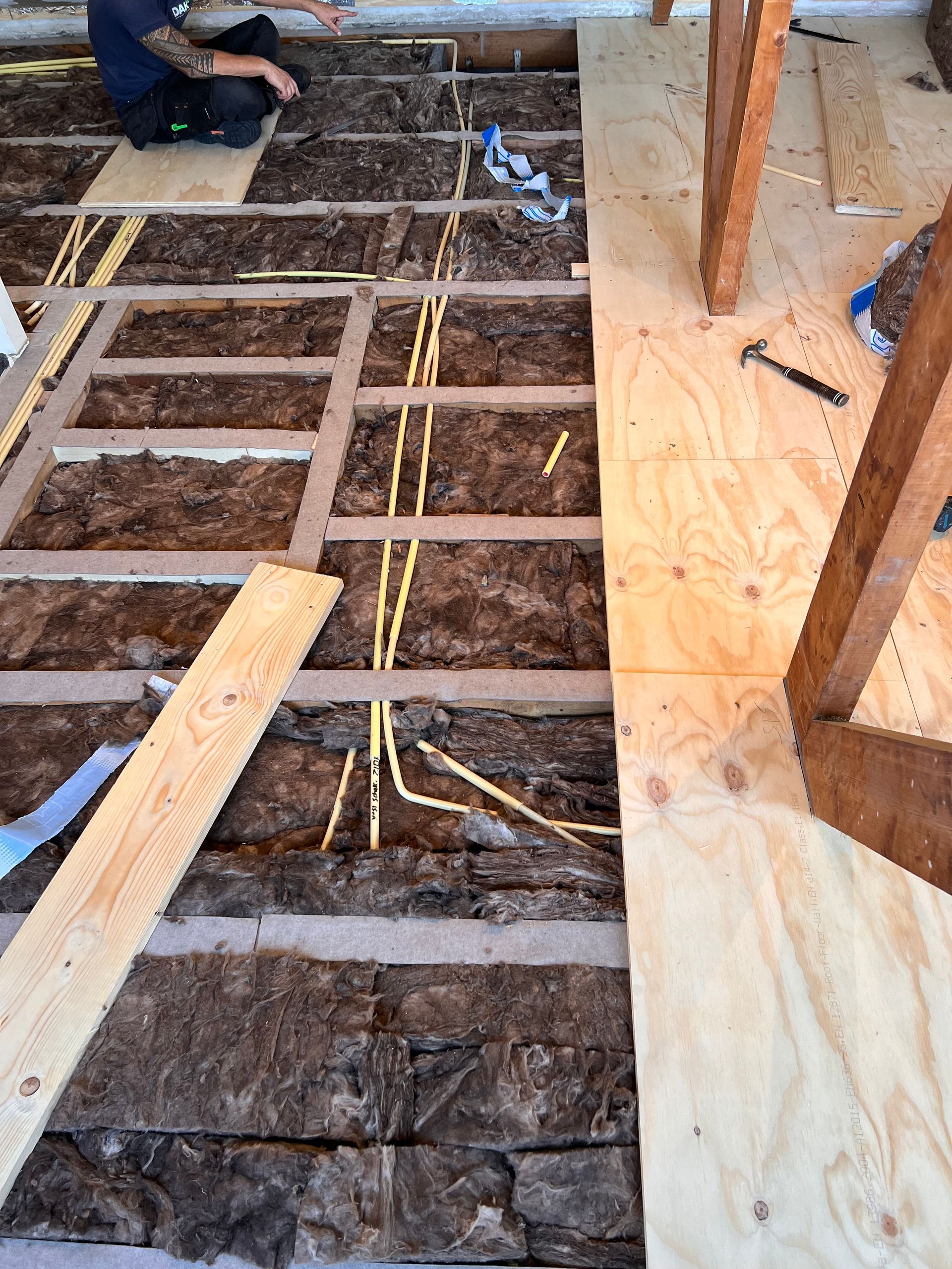 een man werkt op een houten vloer met een hamer en meetlint