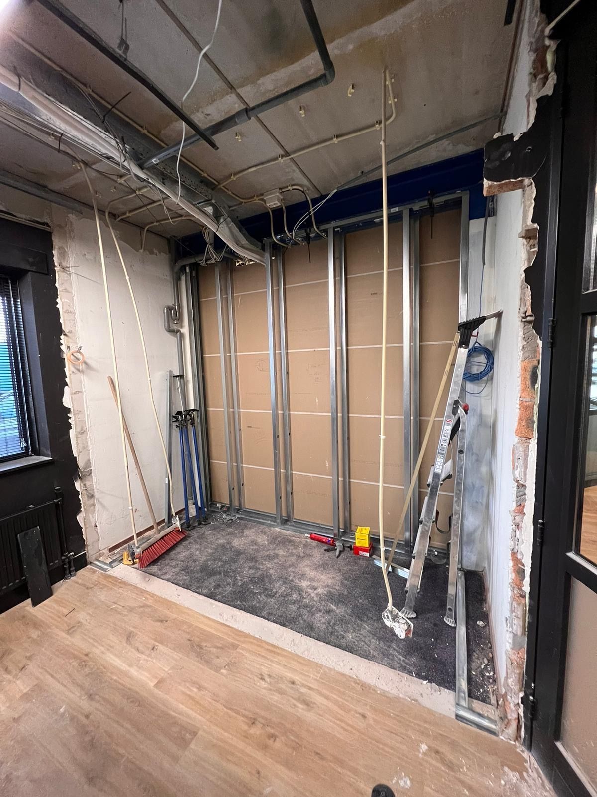 een kamer in aanbouw met een ladder en een bezem