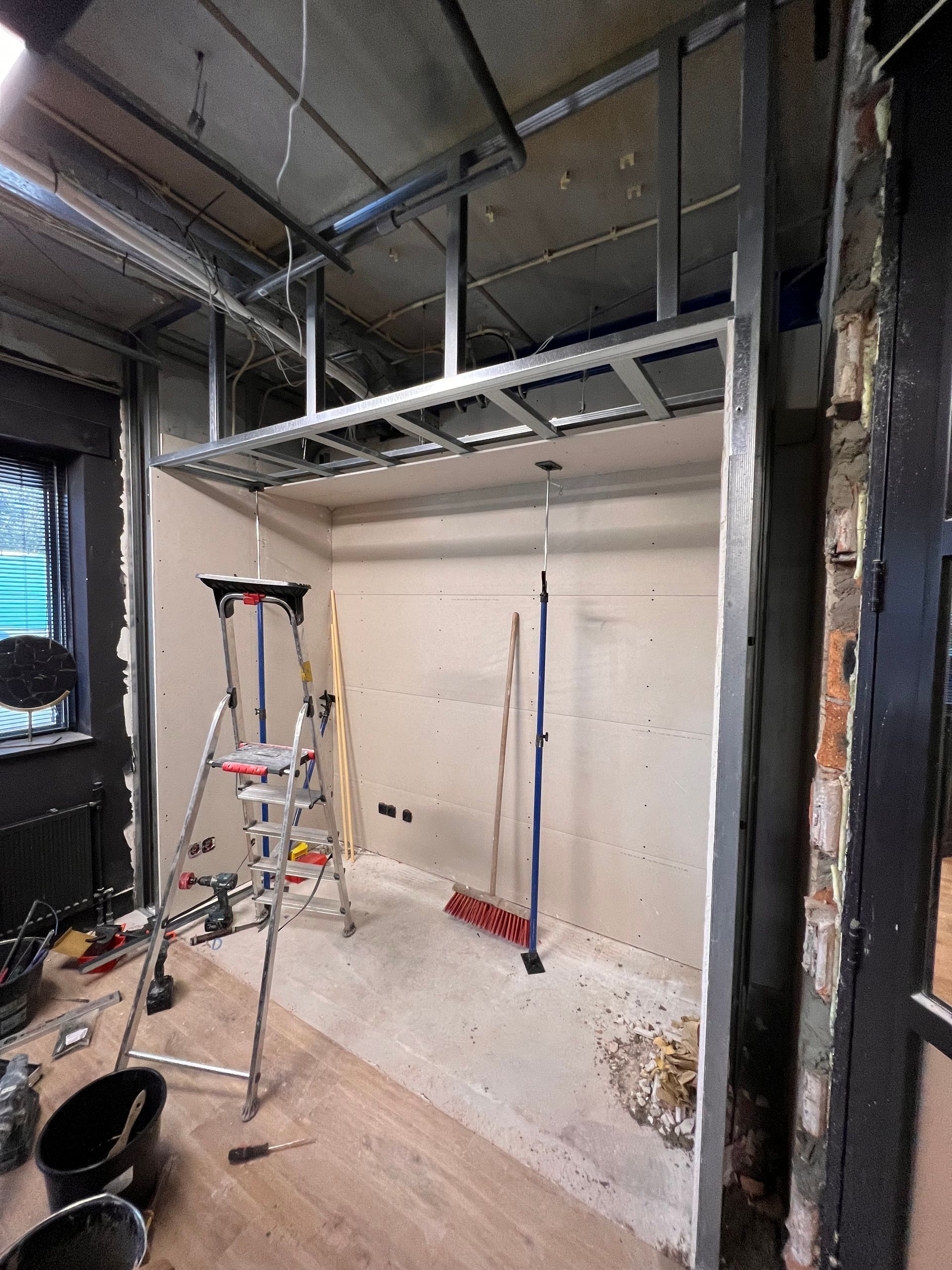een kamer in aanbouw met een ladder en een bezem