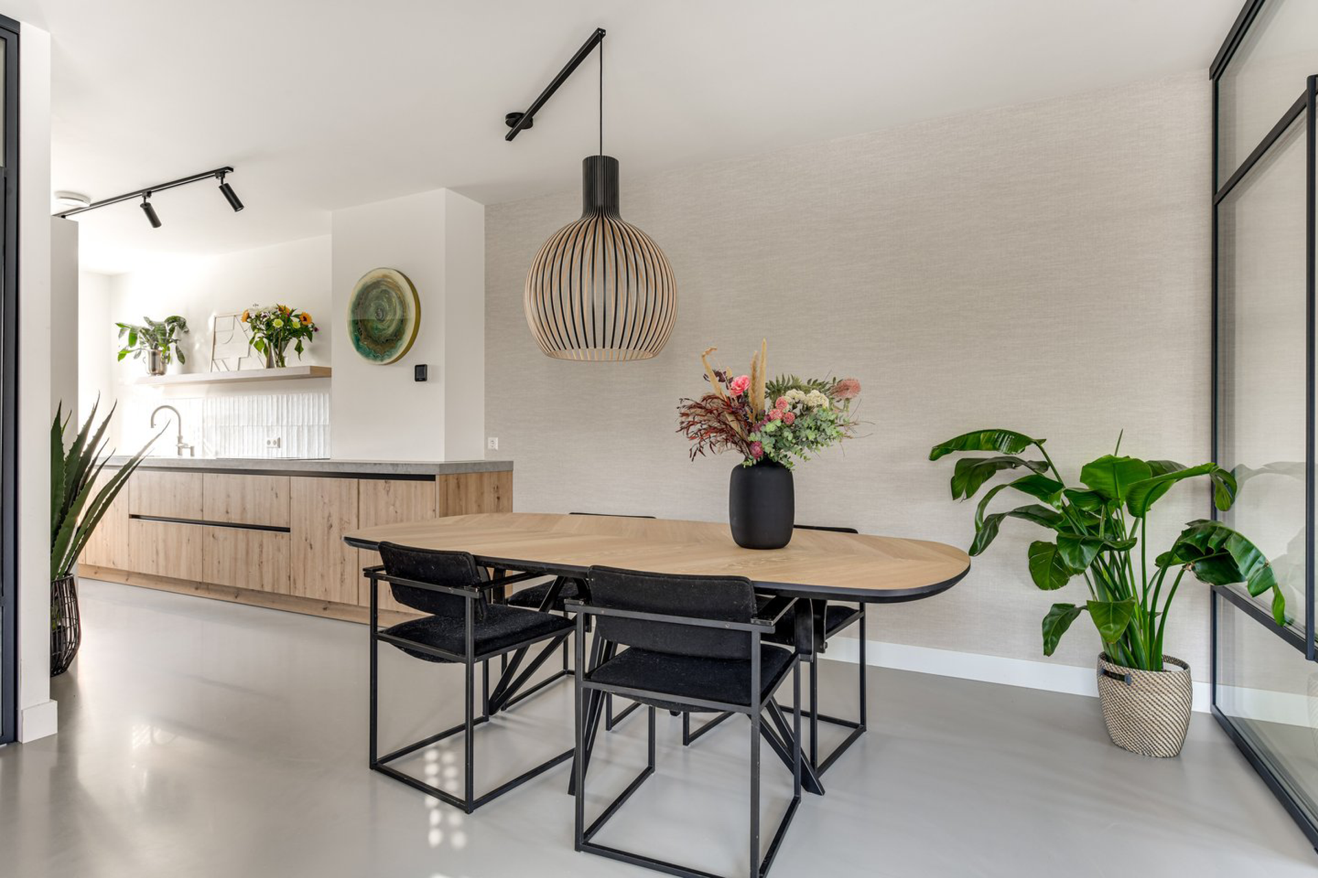 Een eetkamer met een tafel, stoelen en een potplant.