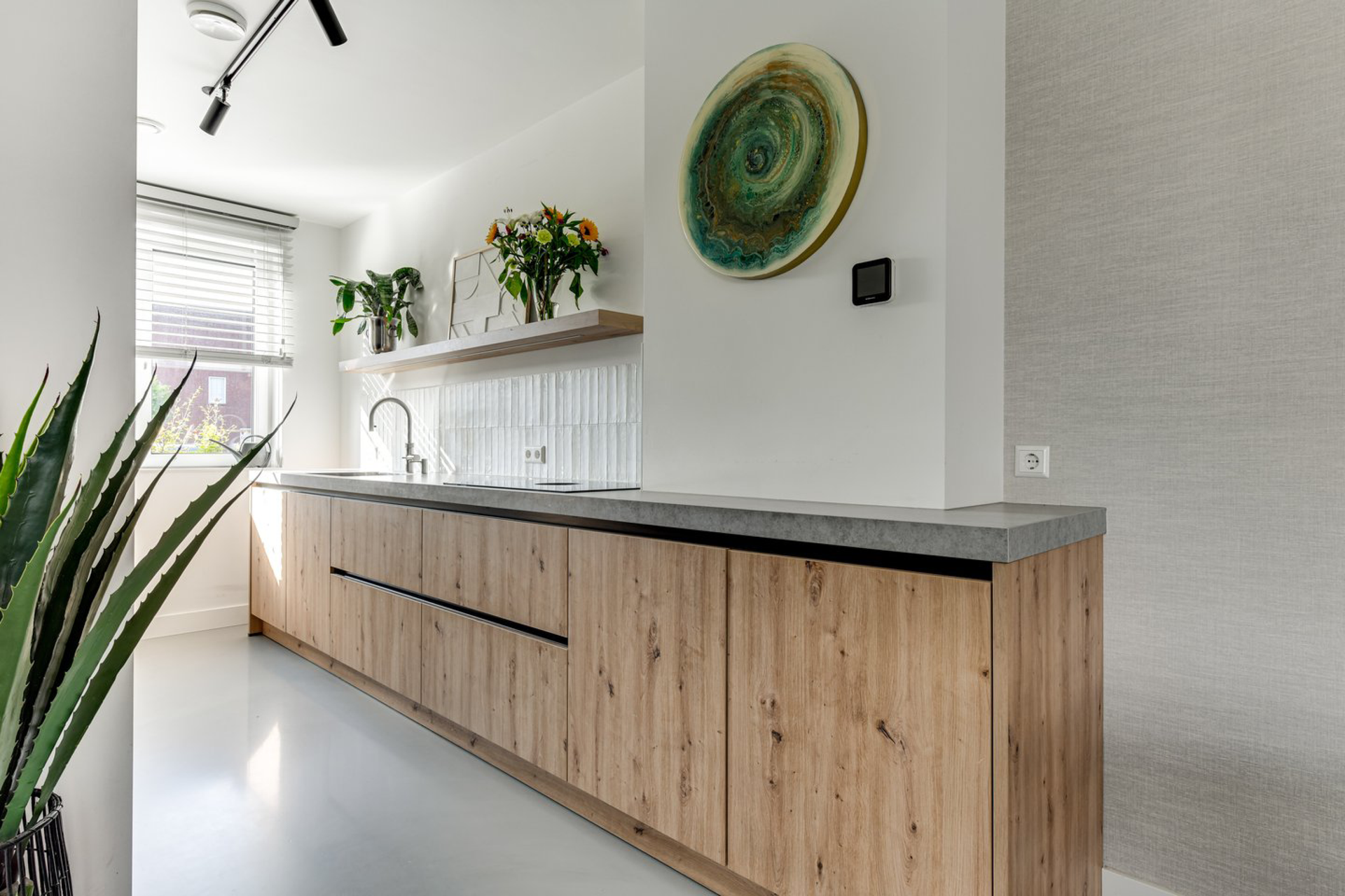 Een keuken met houten kasten en een betonnen aanrechtblad.