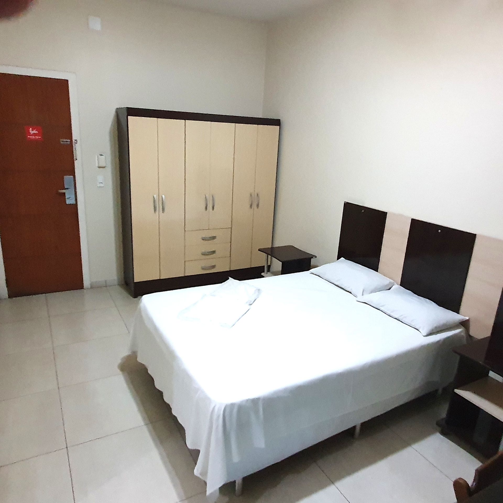 Um quarto de hotel com uma cama king size e um guarda-roupa