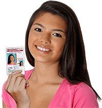 Woman smiling, holding driver's license, wearing a pink shirt.