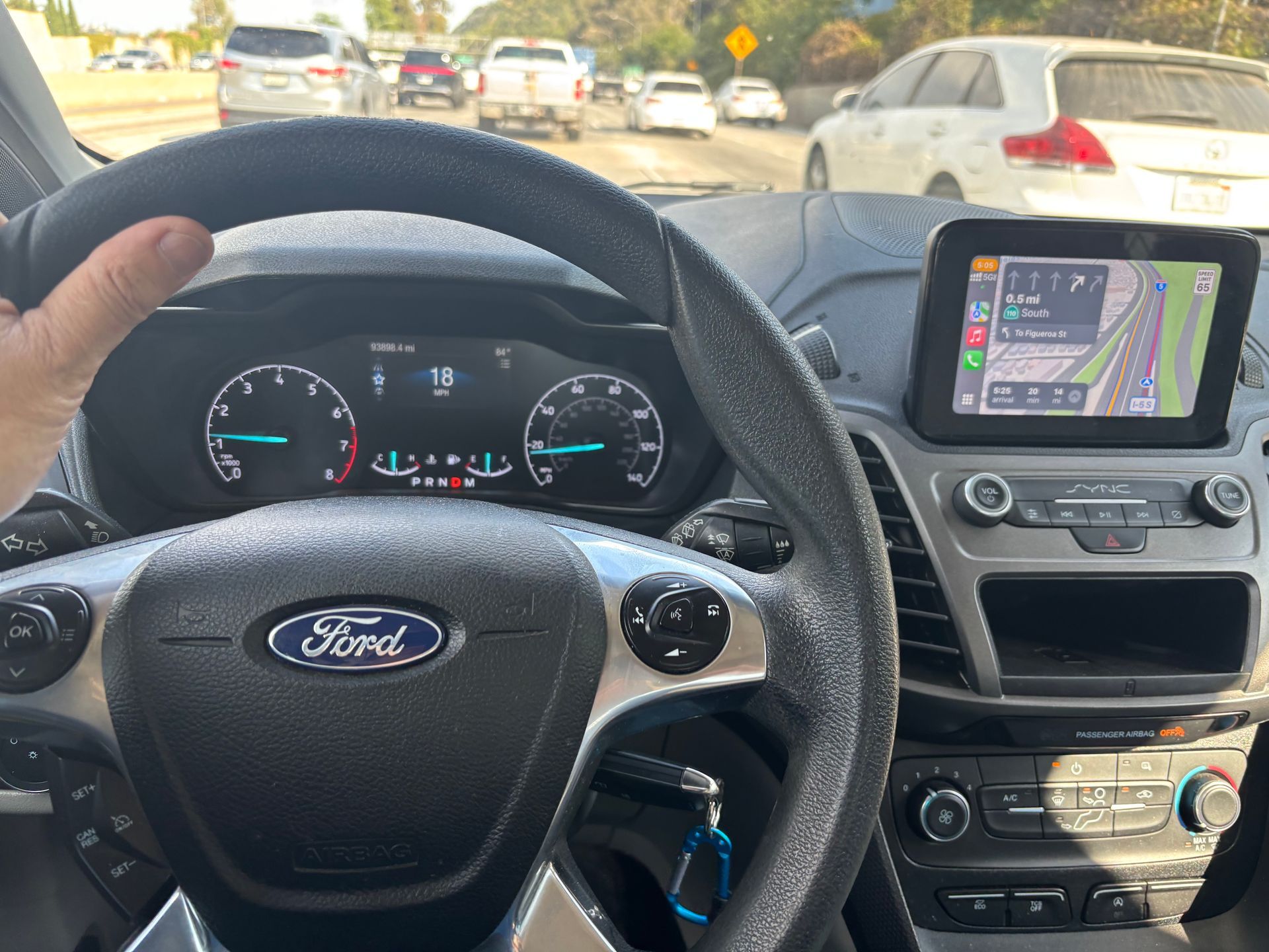 Driver's-eye view: A Ford dashboard with a GPS screen, traffic visible through the windshield.