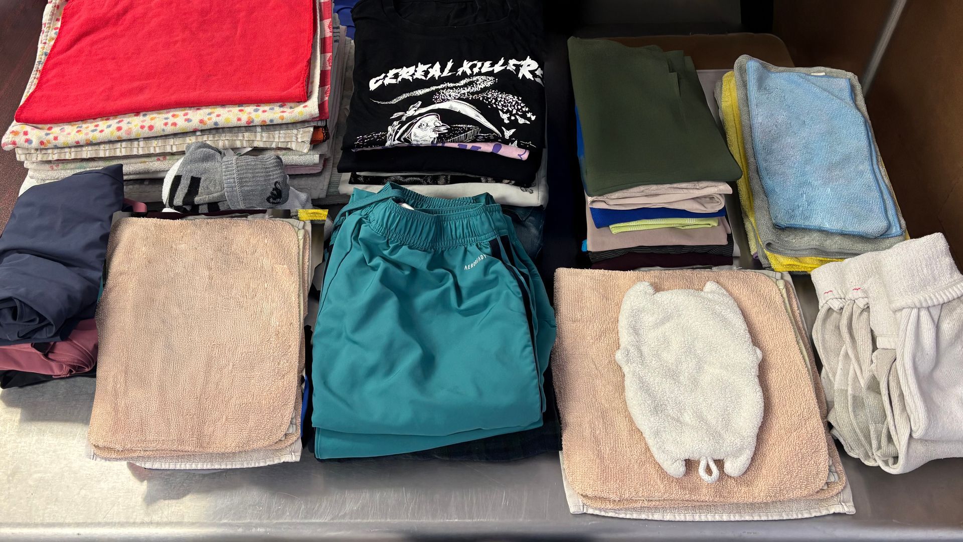 Clothes in laundry baskets and neatly folded on a table. Different colored garments and textiles are present.