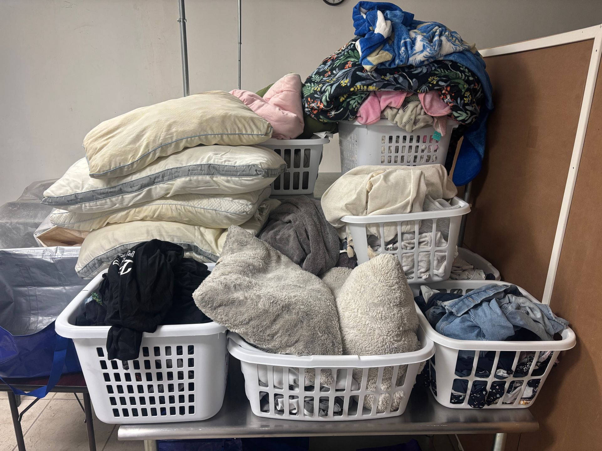 Wrapped blankets on a table, shelves with storage bags in background.