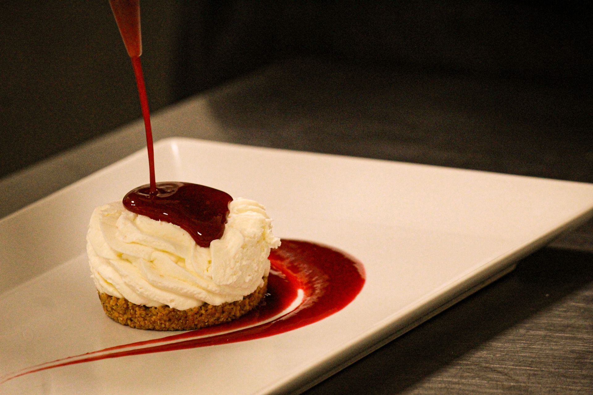 Un piatto bianco condito con una cheesecake e una salsa
