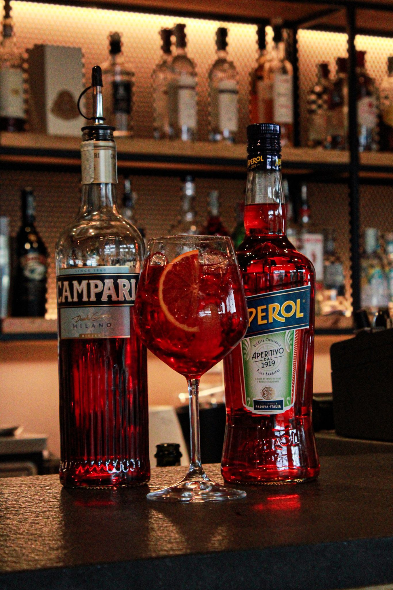 Una bottiglia di campari e una bottiglia di perol sono sul bancone del bar.