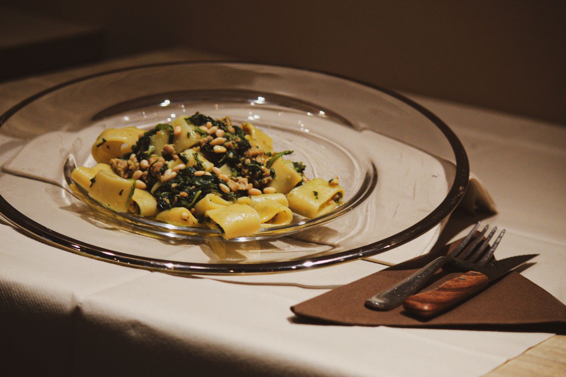 Un piatto di pasta con spinaci e pinoli su un tavolo
