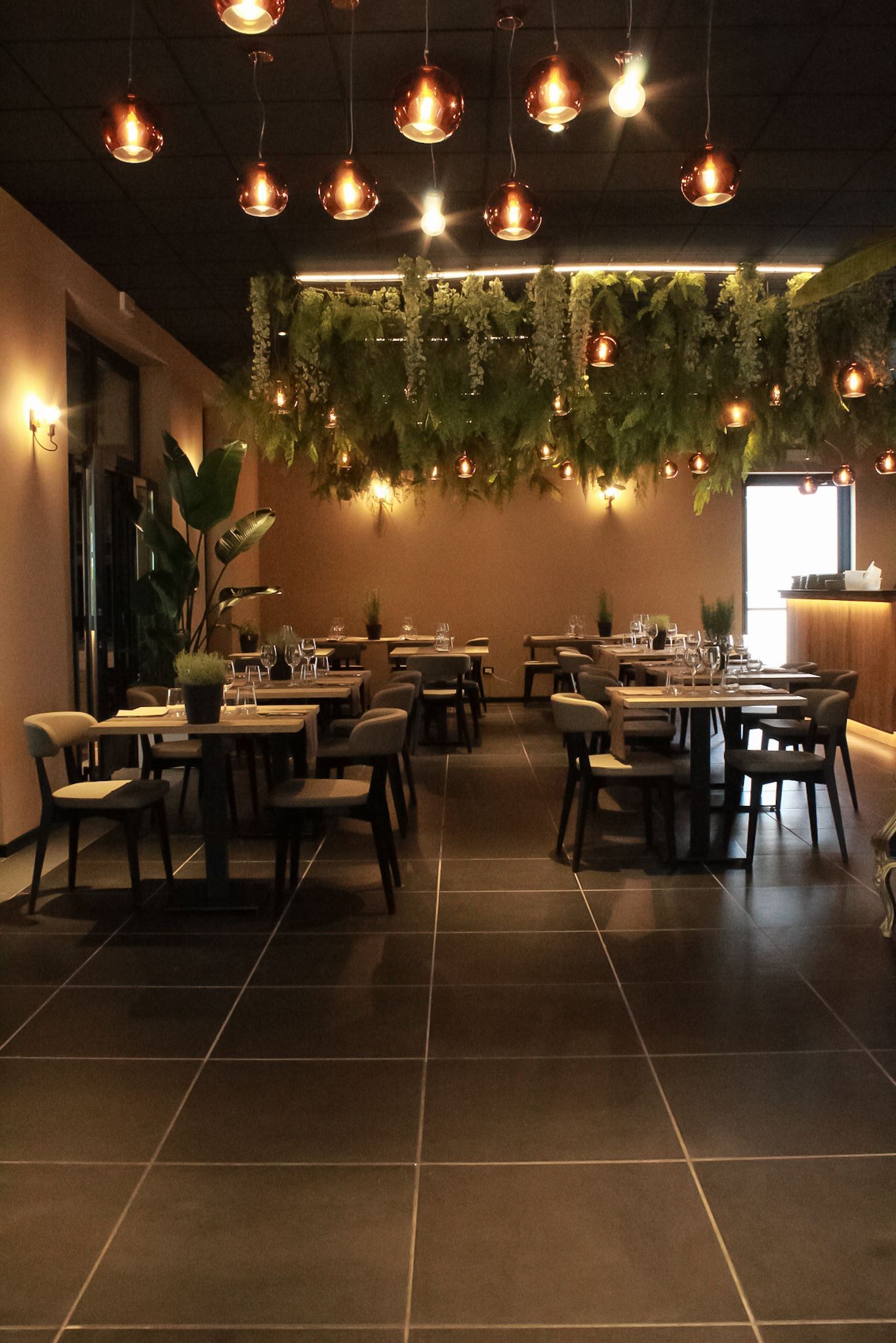 Un ristorante pieno di tavoli, sedie e piante.