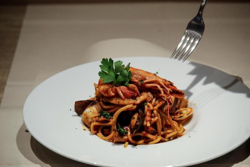 Un piatto bianco condito con spaghetti e pesce