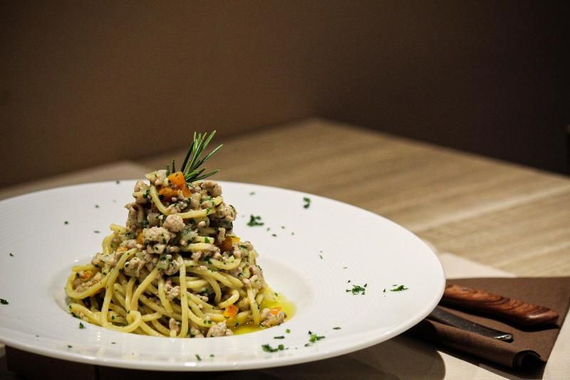 Un piatto di spaghetti con carne e verdure su un tavolo.