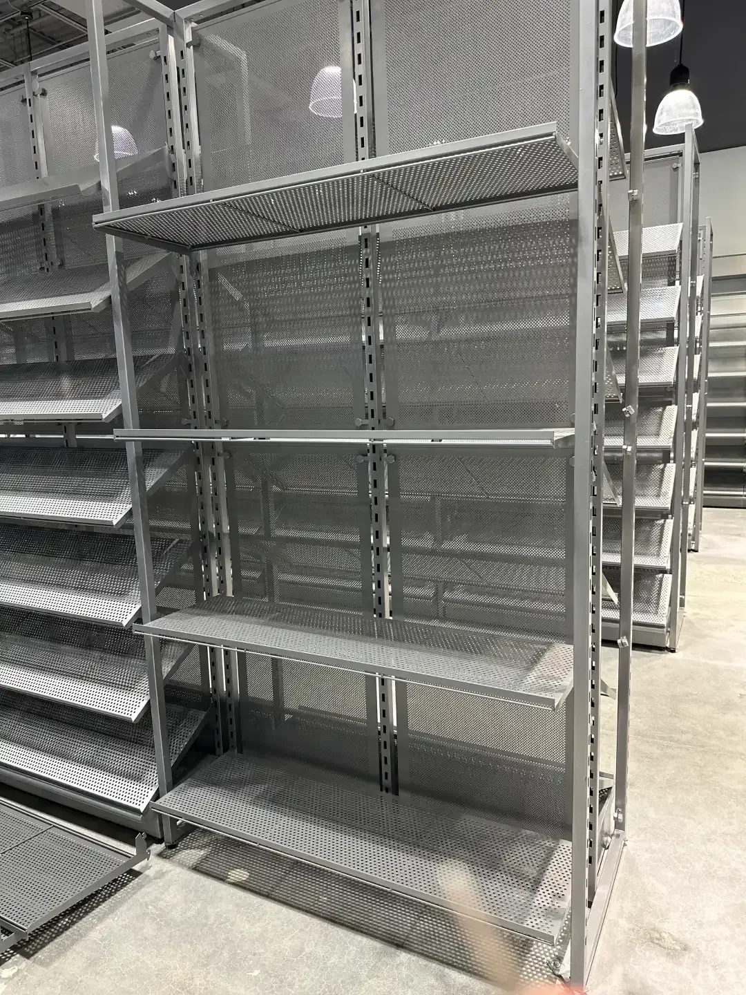 Metal shelving units in a retail setting, with perforated shelves and supports.