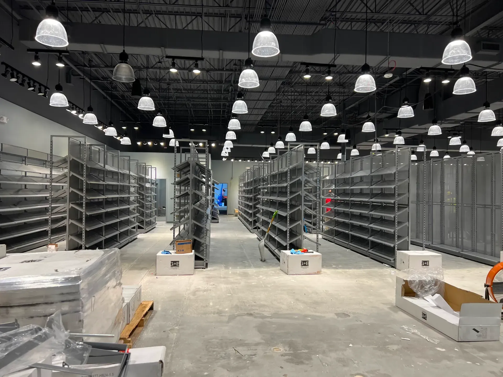Empty commercial space with shelving and lighting fixtures.