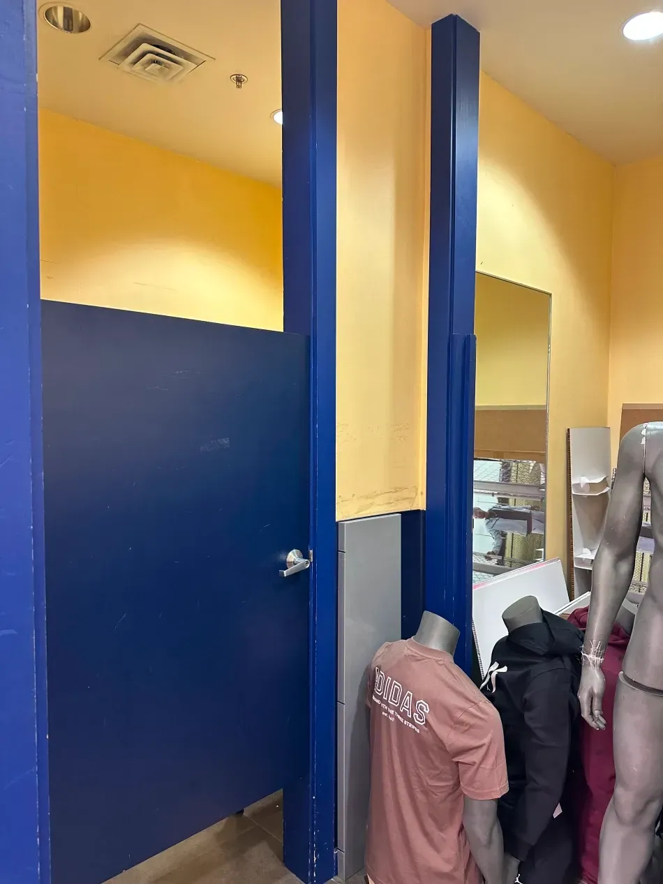 Blue dressing room with mannequin. Yellow and blue walls, mirrors.