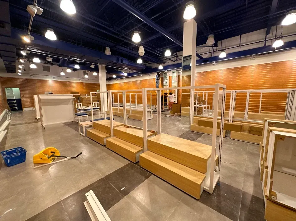 Empty retail space under construction, featuring display fixtures and exposed brick walls.