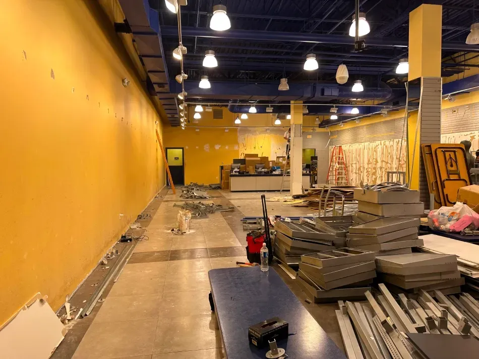 Interior of a building under construction. Yellow walls, blue ceiling, tools and materials scattered throughout.