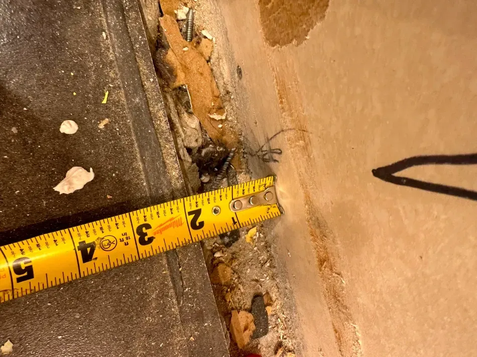 A tape measure next to a wall, showing a gap of approximately 2 inches.