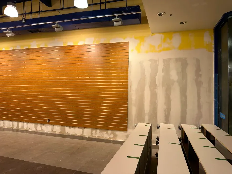 Interior view of a space under construction with an orange textured wall and drywall.