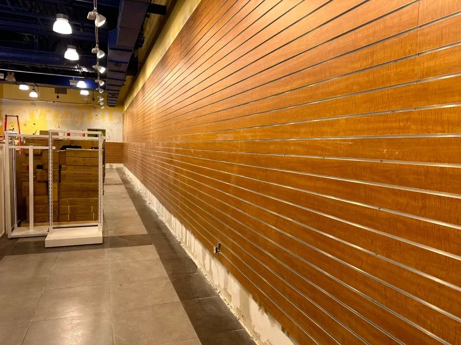 Empty store interior with wood slat walls, concrete floor, and overhead lighting.