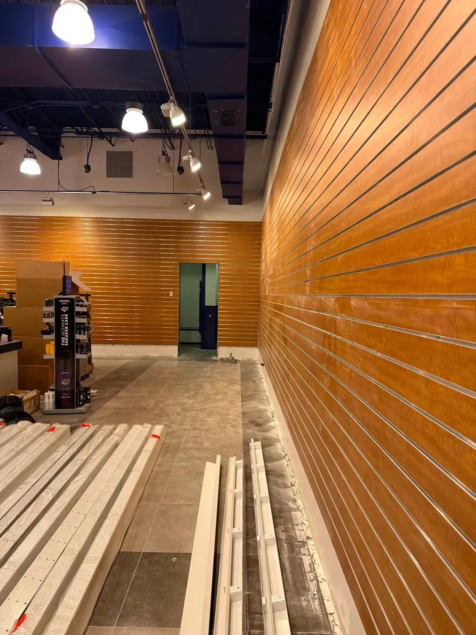 Interior of a retail space, wood-paneled walls, bright lighting, and visible construction materials.
