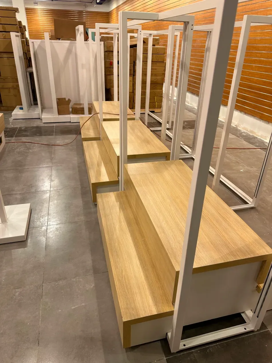 White metal and wood display shelving in a store, partially assembled.