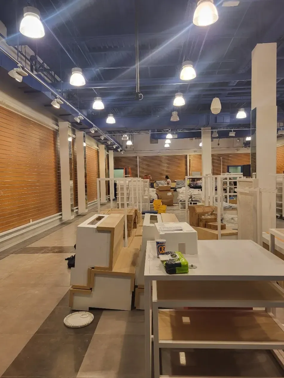 Empty retail space with white fixtures, tan walls, and blue ceiling. Construction in progress.