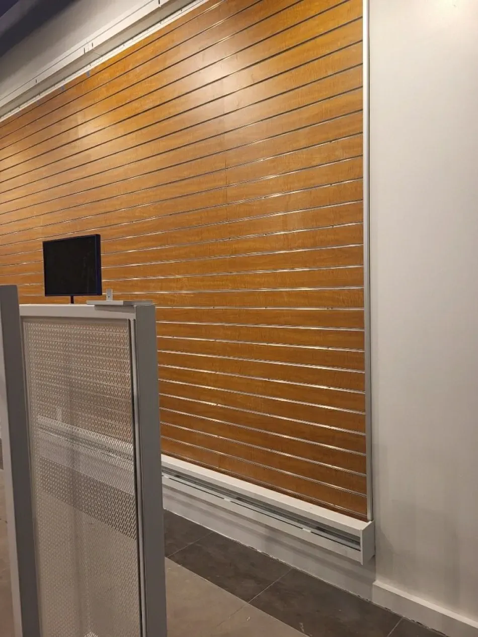 Brown wooden slat blinds cover a window; a small monitor is visible.