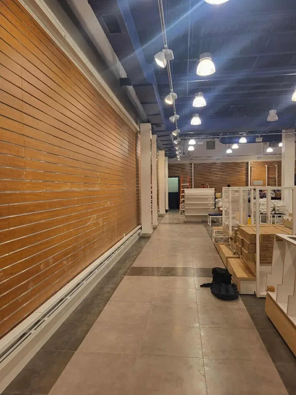 Long, empty commercial hallway with wooden wall panels and overhead lighting.