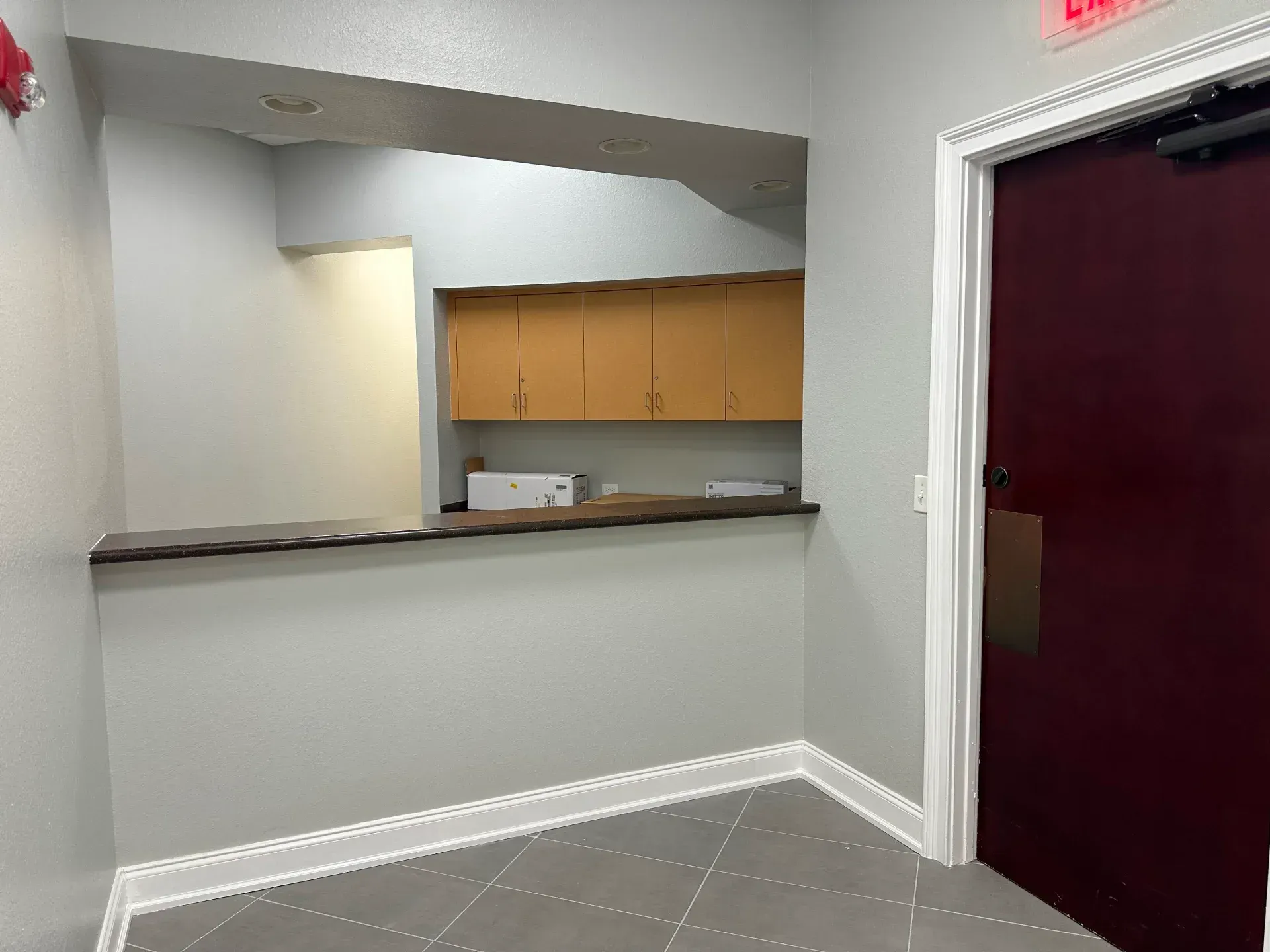 Reception area with a counter, cabinets, and a burgundy door.