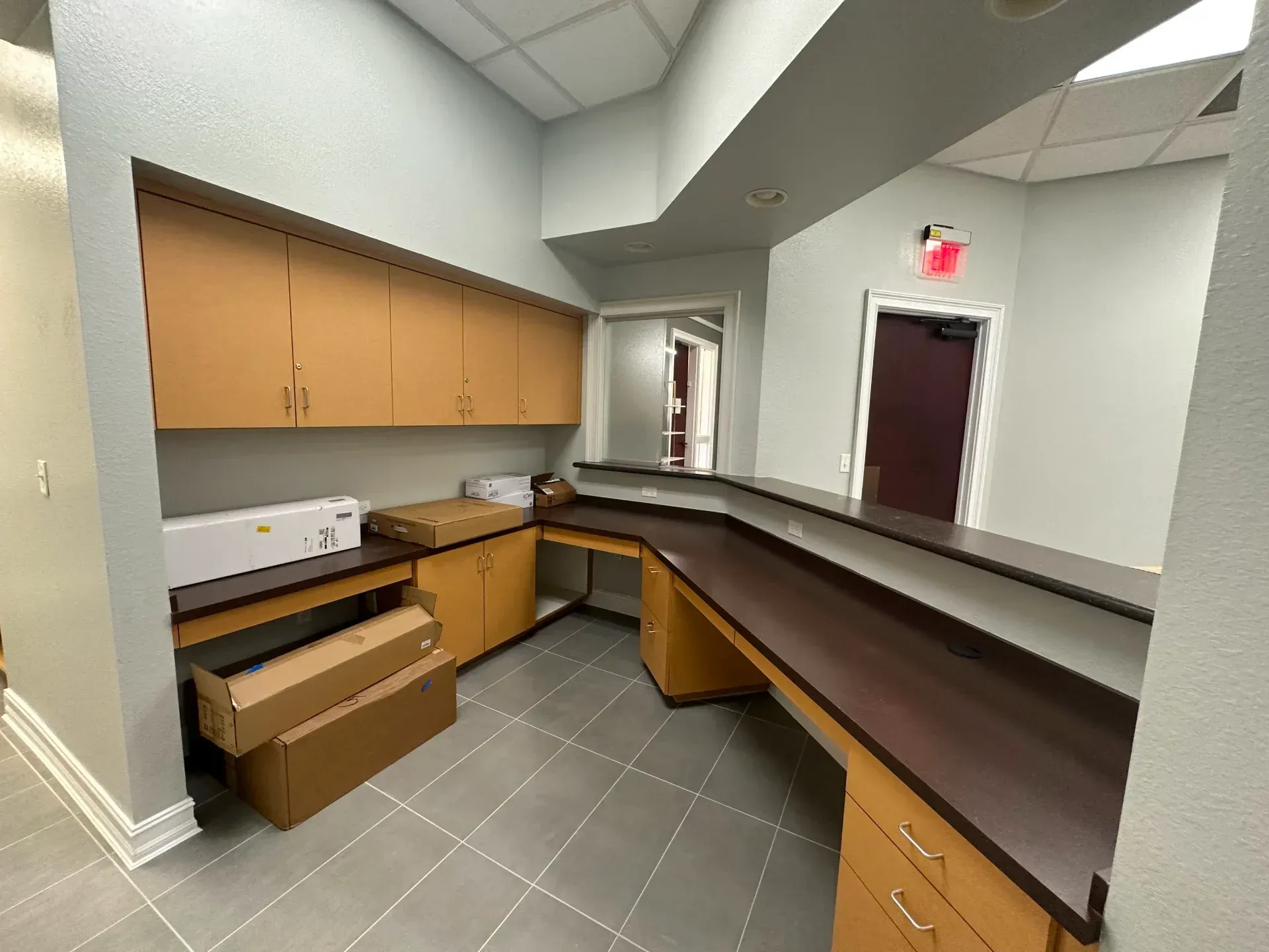 Empty office reception area with cabinets, desk, and emergency exit sign.