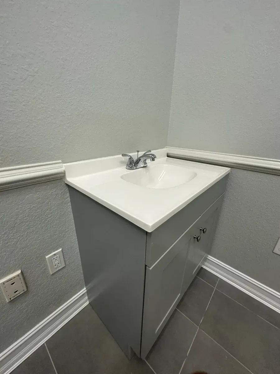 Gray corner bathroom vanity with a white countertop and sink.
