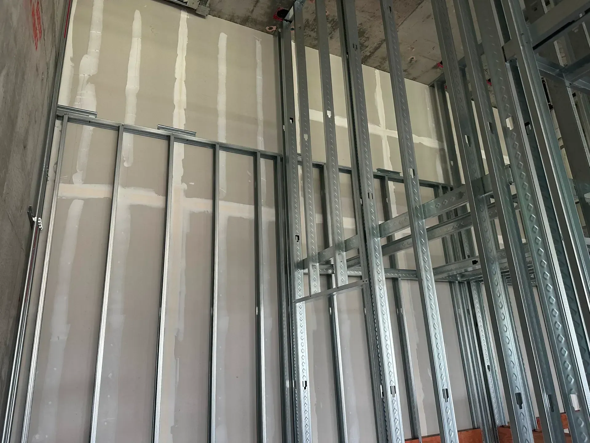 Metal framing and drywall in construction, partially finished interior wall.