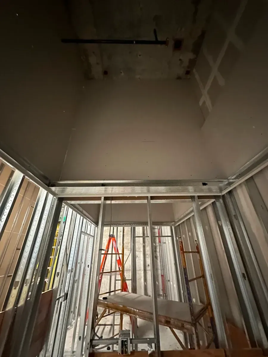 Interior construction view with metal studs, open walls, and a ladder.