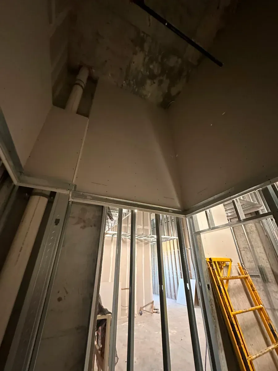 Construction site interior with metal framing, drywall, and scaffolding.