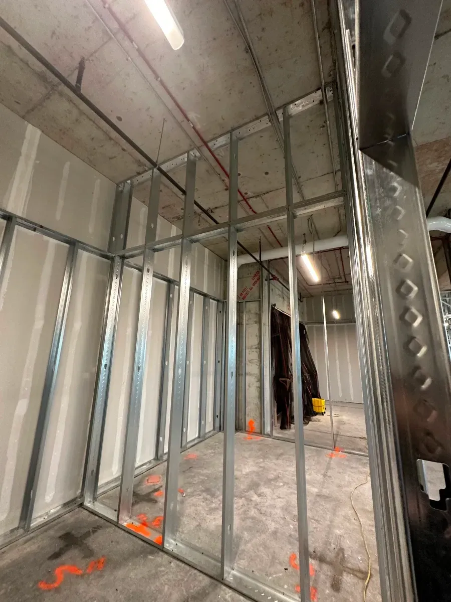 Interior construction site with metal studs, drywall, and unfinished concrete.