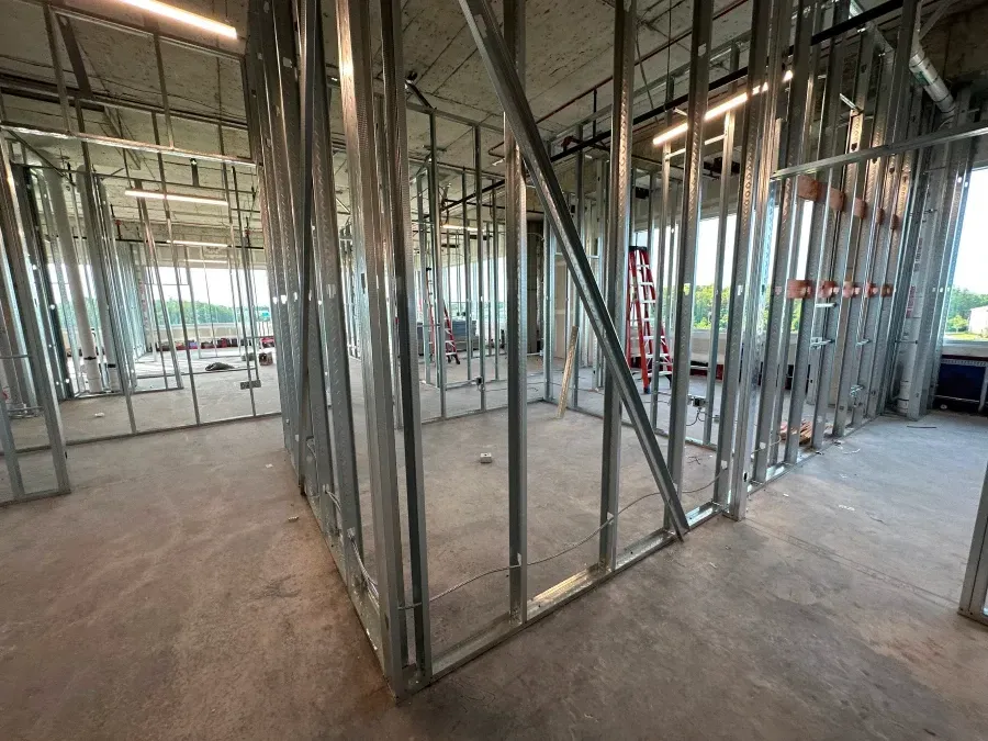 Interior construction site with metal stud framing. Walls and unfinished concrete floor.