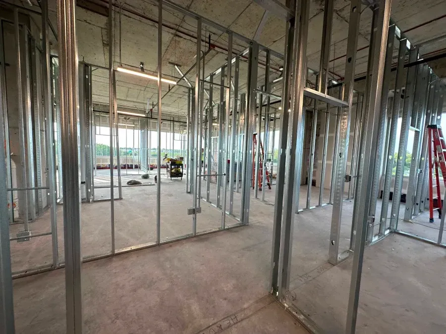 Interior view of a building under construction, metal stud framing for walls is visible.