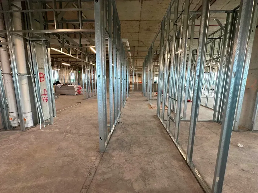 Interior view of a building under construction, showing metal stud wall framing.