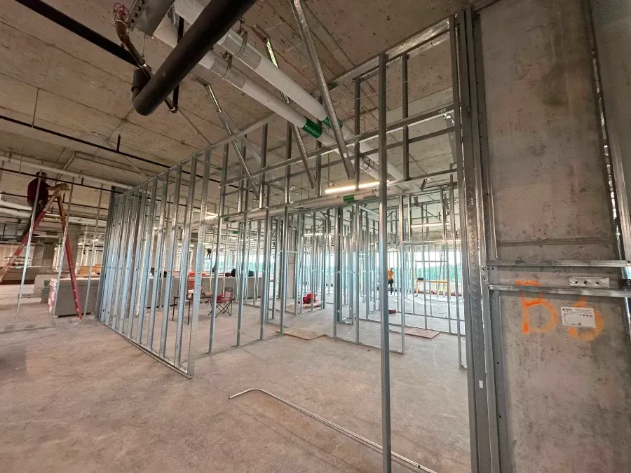 Interior view of a building under construction, metal framing for walls is visible.