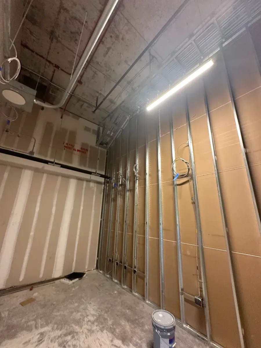 Interior of a construction site with exposed studs, insulation, and partially finished walls.