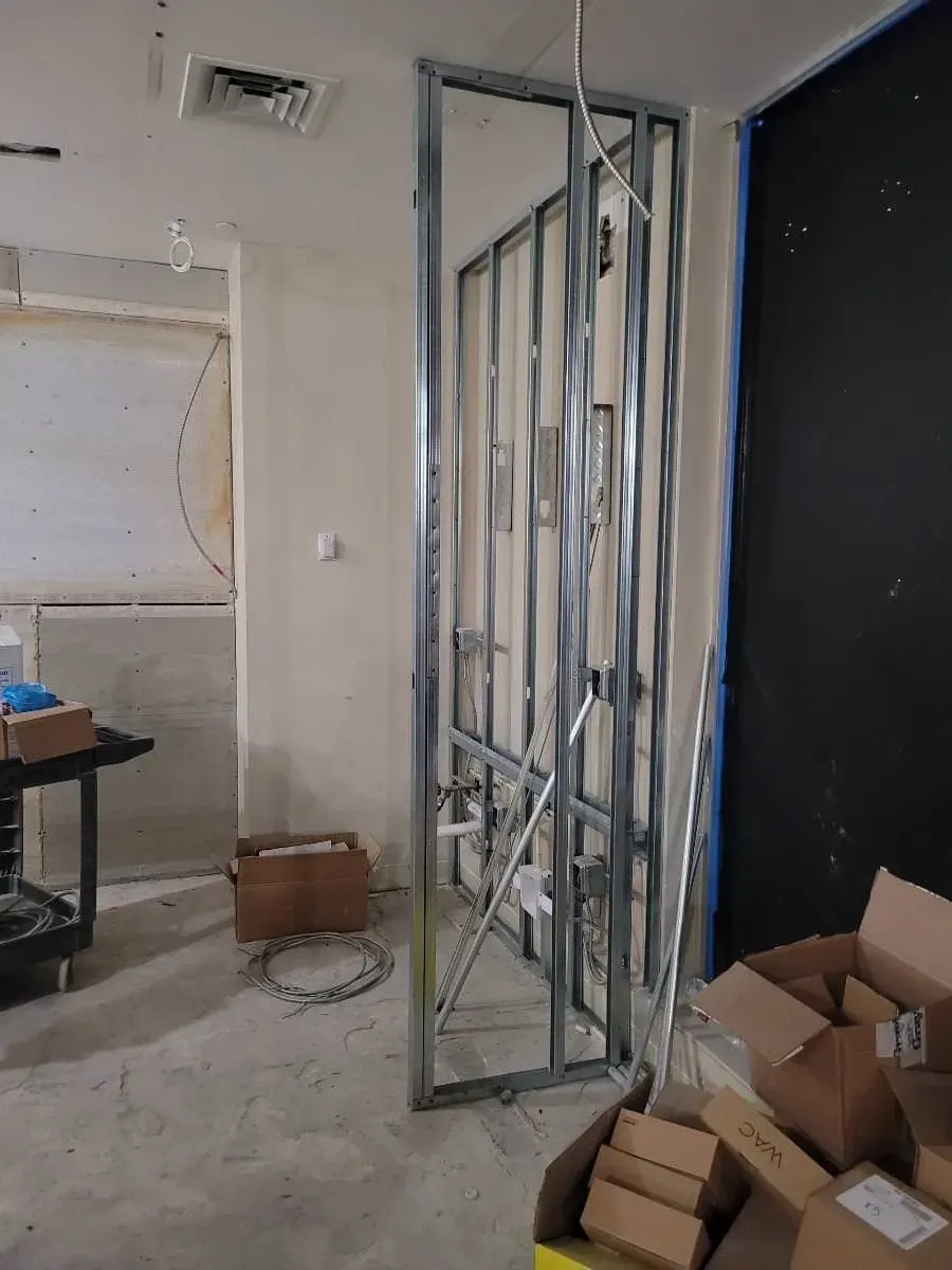 Interior construction with metal studs, electrical wiring, and cardboard boxes.