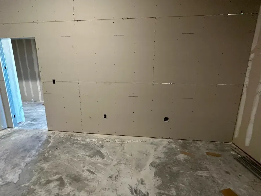 Interior view of a room with unfinished drywall walls and a doorway. Concrete floor.