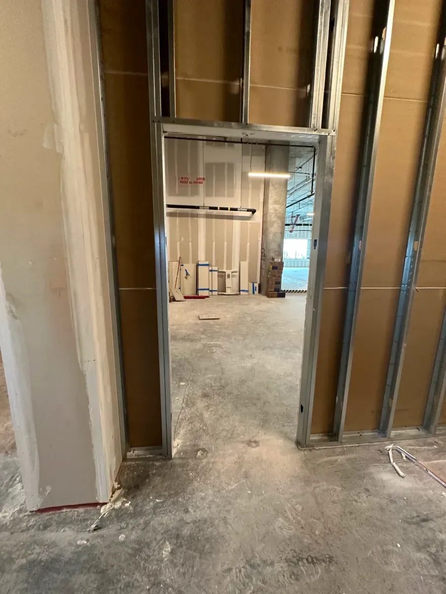 Framed doorway in a room under construction, showing metal studs and unfinished walls.