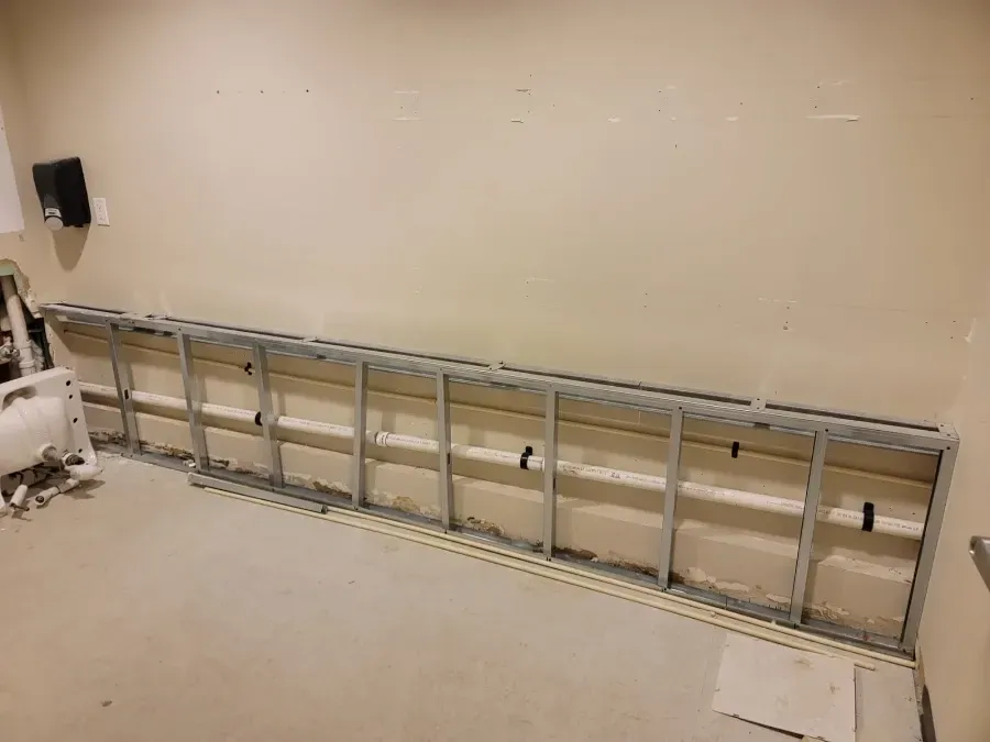Metal frame structure attached to a beige wall, possibly for drywall or shelving.